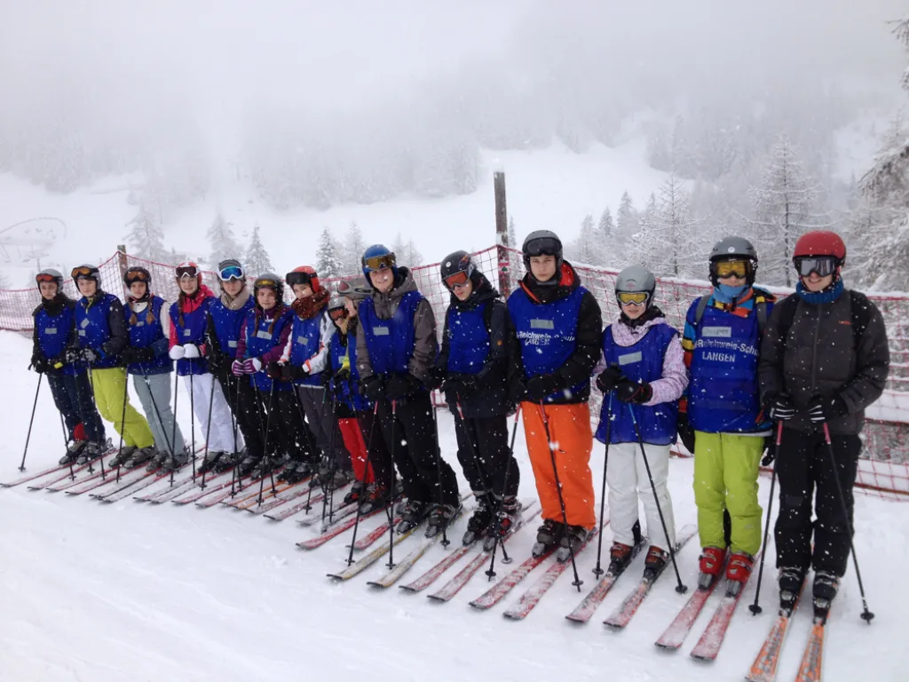 Skigruppe steht in einer Reihe an der Talstation.
